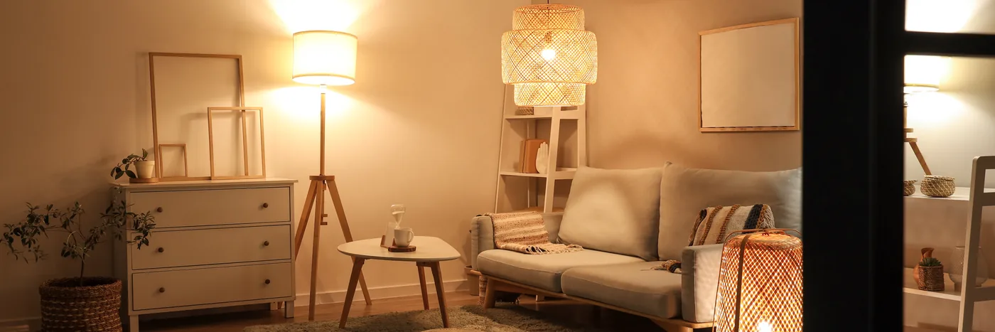 A living room in the evening lit only by a floor lamp and a shaded pendant.